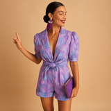Short jumpsuit for women with vibrant print and waist-accentuating belt, perfect for summer days or casual evening looks.