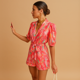 Short jumpsuit for women with vibrant print and waist-accentuating belt, perfect for summer days or casual evening looks.